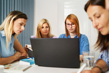 Group of women female only colleagues working together on project sitting by the desk using laptop at work in the office - Millennial boss and entrepreneurs having meeting brainstorming concept