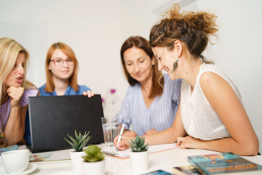 Group Of Women Female Only Colleagues Working Together On Project Sitting By The Desk Using Laptop At Work In The Office - Millennial Boss And Entrepreneurs Having Meeting Brainstorming Concept