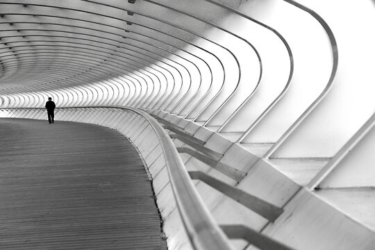 hombre paseando  por un puente  de estructura de hierro pintado de blanco.