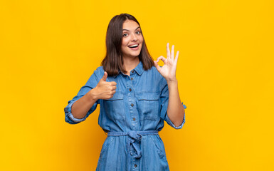 young pretty woman feeling happy, amazed, satisfied and surprised, showing okay and thumbs up...