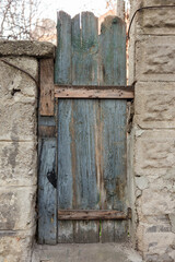 Old wooden fence, a gate with the remains of peeling blue paint. Rural landscape.