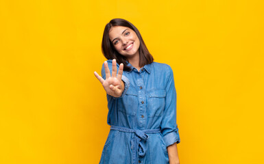 young pretty woman smiling and looking friendly, showing number four or fourth with hand forward,...