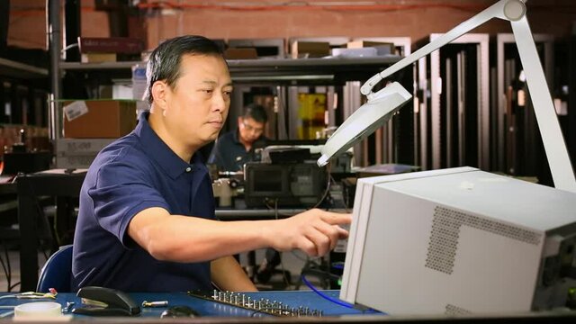 Asian electrical engineer testing computer component