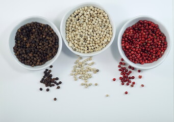 Flat layout composition of three colors of peppercorn in white bowls on a white background 