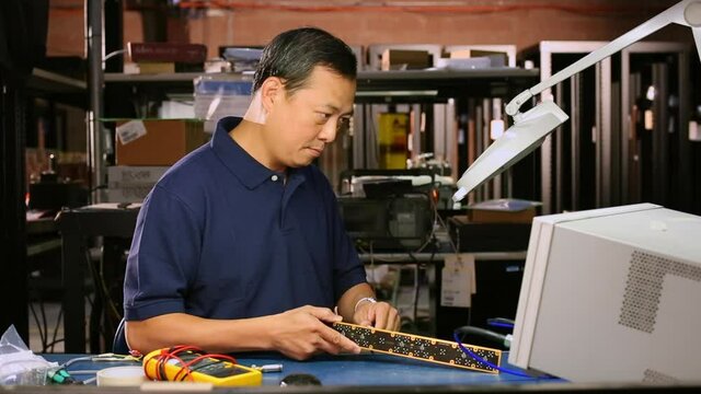 Asian electrical engineer testing computer component