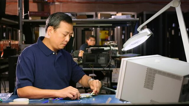 Asian electrical engineer testing computer component