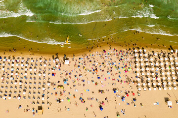 Fototapeta na wymiar Aerial view from a drone. Beach with tourists, sunbeds and umbrellas. Travel background. Travel and vacation concept. Top view