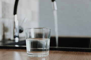 Glass of fresh cold water on table in kitchen