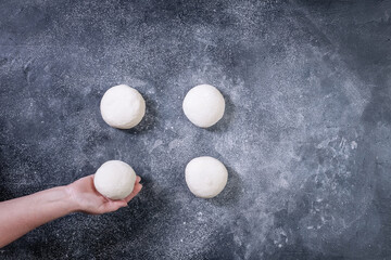 Chef making dough for pizza on dark backrground