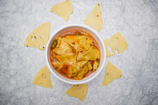 Papad ki sabzi an Indian Rajasthani style curry side dish. Raw or roasted paapad fried made in to gravy side dish. It is a staple in north west India. Isolated in a bowl in white background.