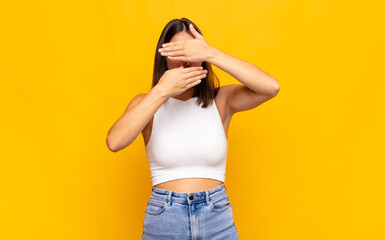 young pretty woman covering face with both hands saying no to the camera! refusing pictures or...