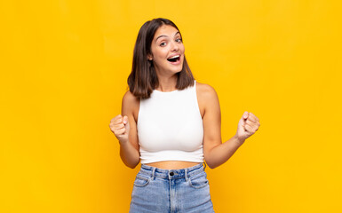 young pretty woman feeling happy, positive and successful, celebrating victory, achievements or...