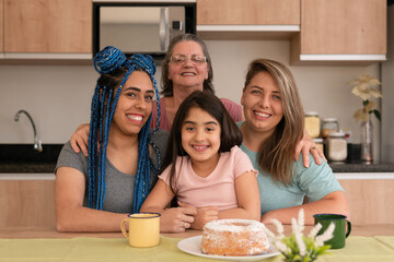 Lovely brazilian lesbian couple with daughter smiling in kitchen home, indoors. Lgbtq family, happiness, affection, love, care concept..