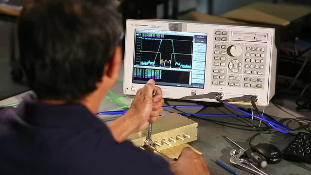 Asian electrical engineer adjusting settings on antenna component
