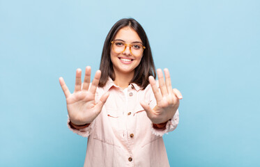 young pretty woman smiling and looking friendly, showing number nine or ninth with hand forward,...