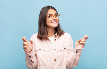 young pretty woman crossing fingers anxiously and hoping for good luck with a worried look