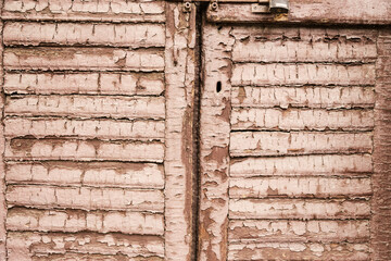 Wood background, texture with the remains of old cracked paint. Old wooden doors painted with brown paint and closed with a metal padlock.