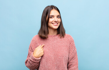 young pretty woman looking proud, confident and happy, smiling and pointing to self or making...