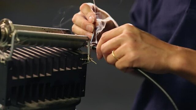 Asian worker using soldering iron in technology industry