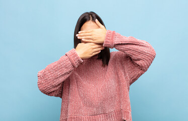 young pretty woman covering face with both hands saying no to the camera! refusing pictures or...