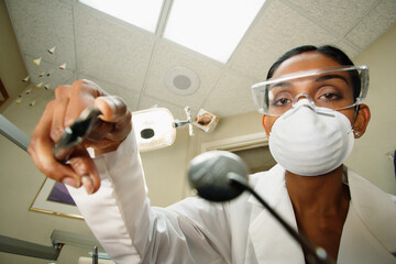 Female dentist reaching towards the camera with pliers