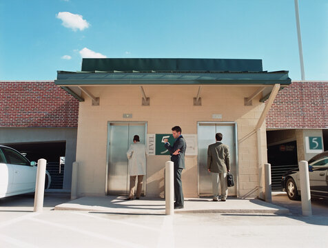 Businesspeople waiting for elevators at parking garage
