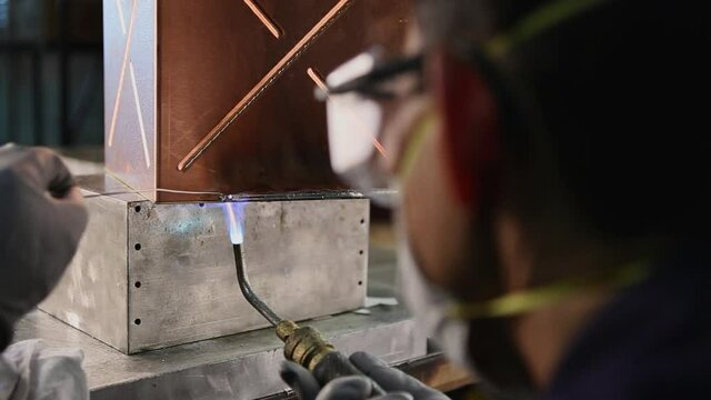 Asian worker soldering copper box in technology industry