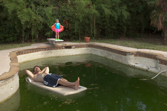 Man floating in dirty swimming pool