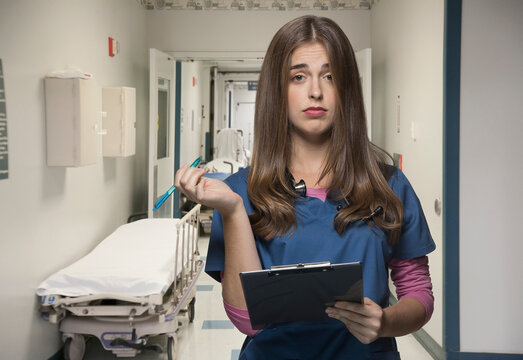 Overworked nurse holding clipboard in hospital hallway