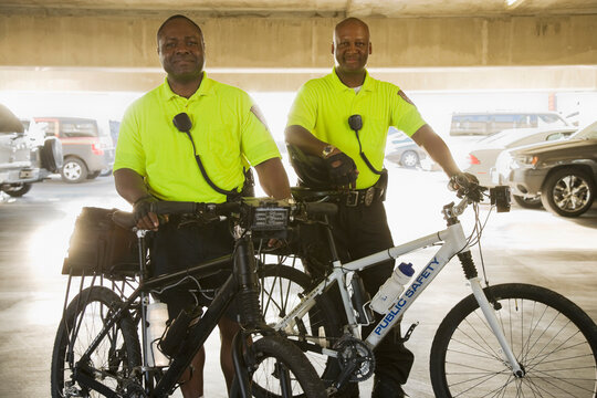 Portrait of police officers with bicycles standing in parking lot