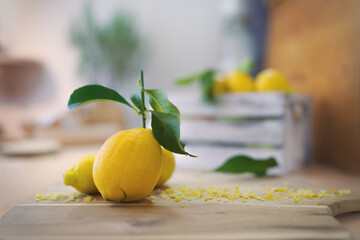 Ripe lemons lying on a wooden board with grated lemon peel.