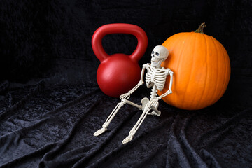 Fall fitness, orange pumpkin, red kettlebell, and white skeleton, on a black velvet background
