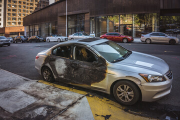 Burnt car from the side on a street next to apartment buildings in Lower East Side, Manhattan