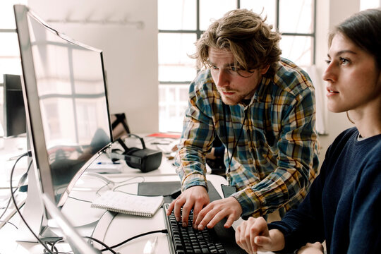 Businessman typing while coworker looking at computer in office