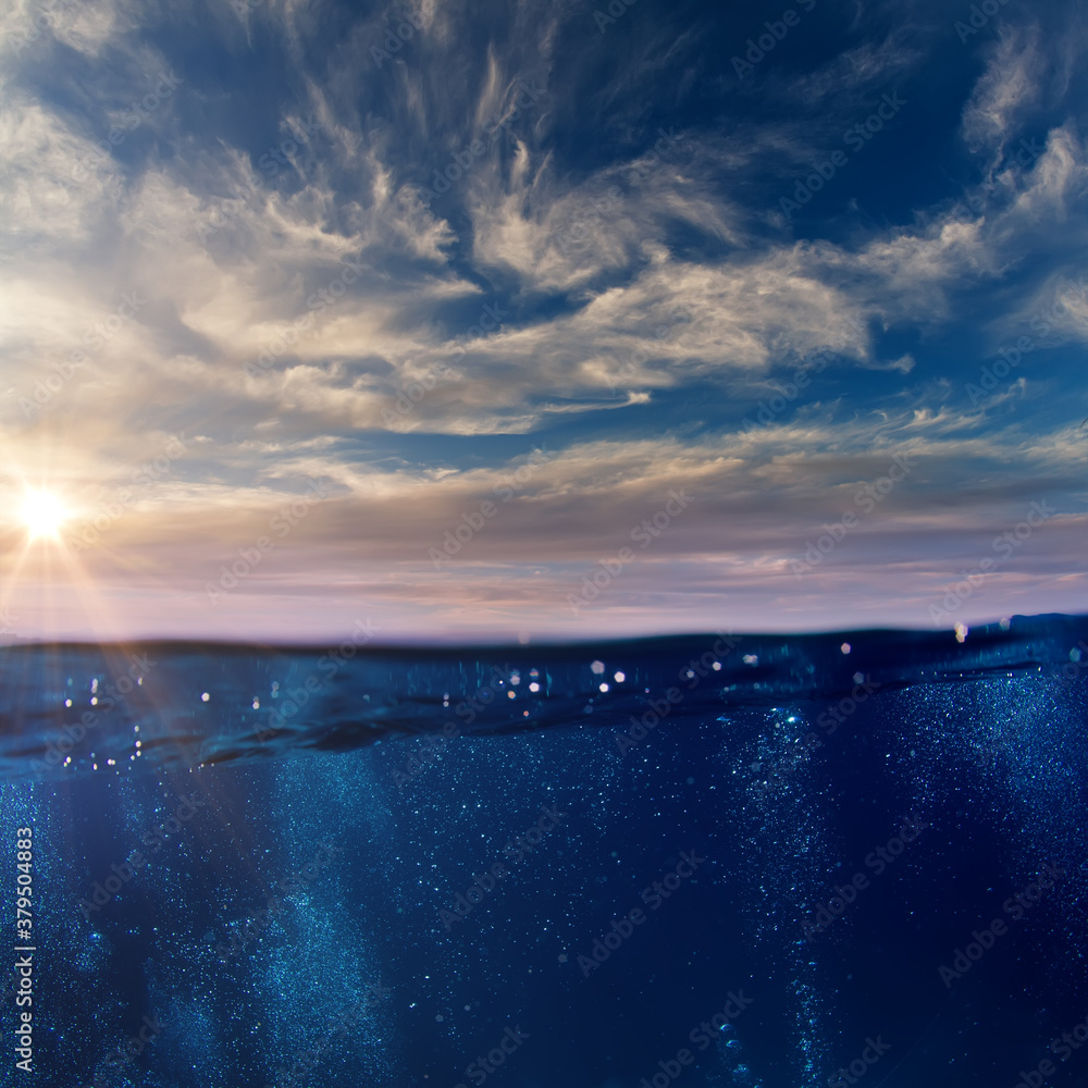 Wall mural cloudy sky with the sun splitted by waterline to underwater and air parts as design template