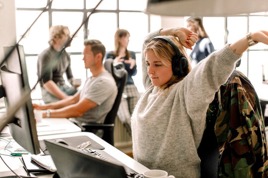 Female entrepreneur stretching while looking at computer in office