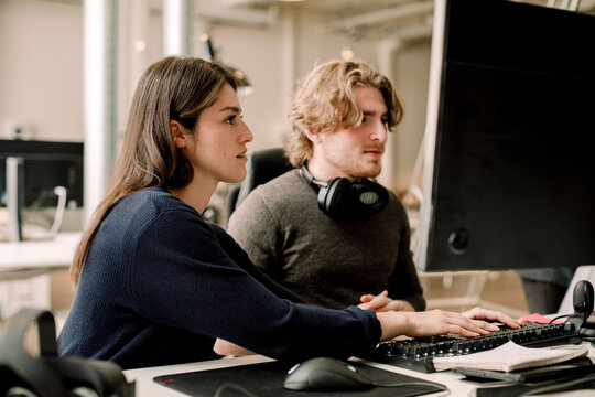 Side view of female entrepreneur working with coworker in office