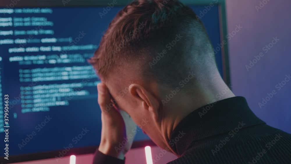 Wall mural rear view of developer having stress in the office. man programmer has a headache at office work. ov