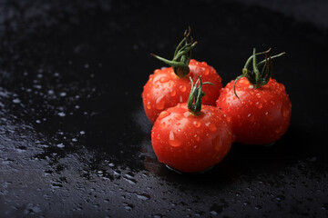 Grupo de Tomates Cherry frescos mojados sobre mesa negra   