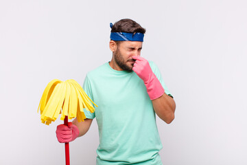 young man feeling disgusted, holding nose to avoid smelling a foul and unpleasant stench