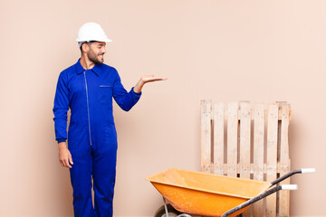 young man feeling happy and smiling casually, looking to an object or concept held on the hand on...