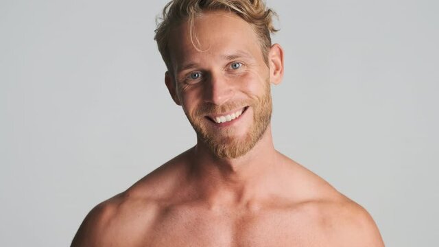 Handsome smiling blond bearded man happily posing on camera isolated. Male model posing in studio