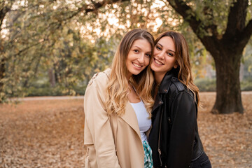 Fototapeta premium Two female Caucasian friends in Fall season in park, love and affection to each other 