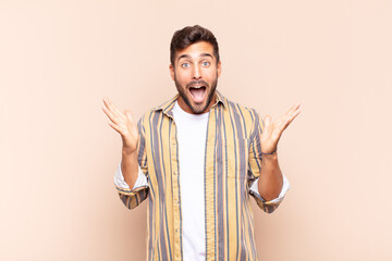 young man feeling happy, excited, surprised or shocked, smiling and astonished at something...