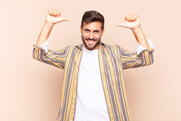 young man feeling proud, arrogant and confident, looking satisfied and successful, pointing to self