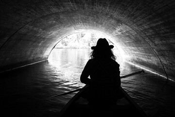A woman canoeing under a bridge.  - 379510829