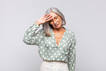 gray haired woman looking stressed, tired and frustrated, drying sweat off forehead, feeling...