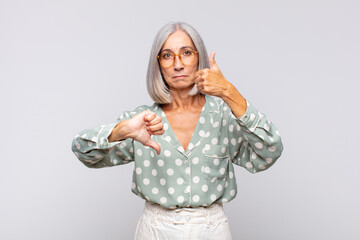 gray haired woman feeling confused, clueless and unsure, weighting the good and bad in different...