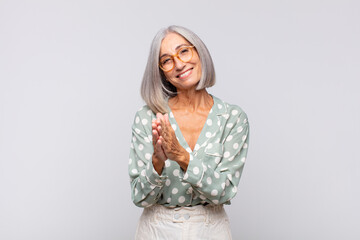 gray haired woman feeling happy and successful, smiling and clapping hands, saying congratulations...