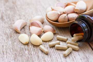 Selective focus. Garlic capsules with garlic bulb and clove isolated on wood table background.